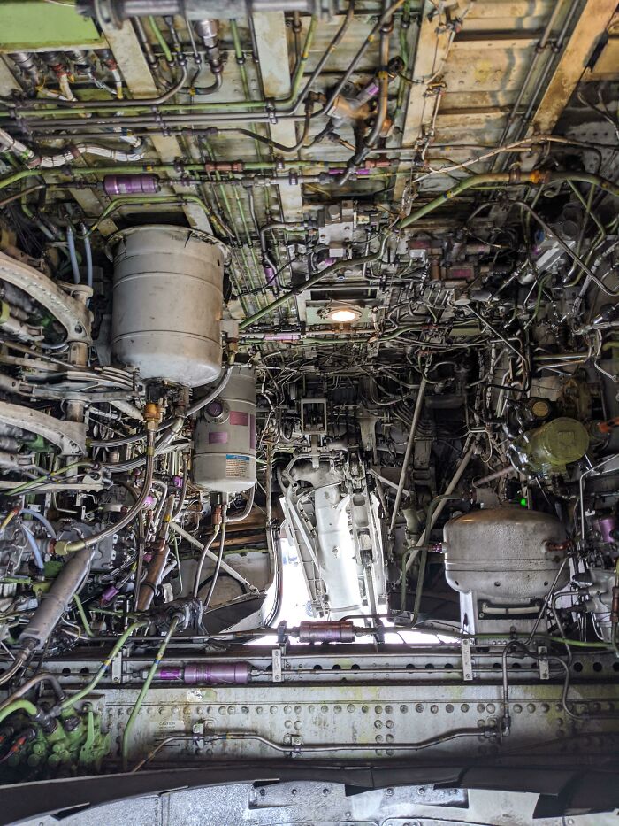 Intricate inside view of mechanical object showing extensive pipes, wires, and components in a complex industrial setup.