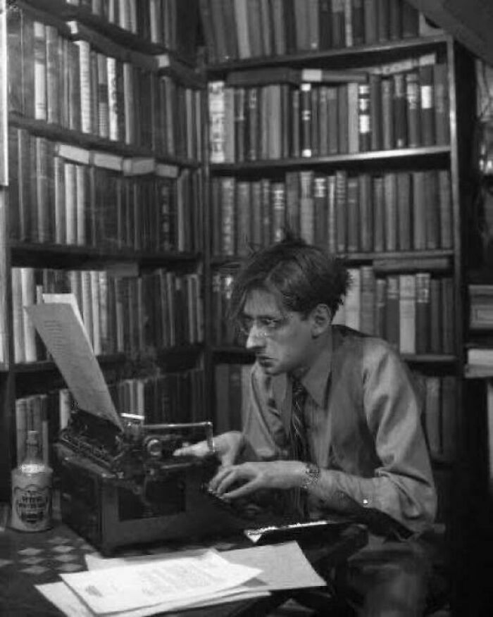 Man intensely typing on a vintage typewriter surrounded by books, a unique historical photo with a deep backstory.