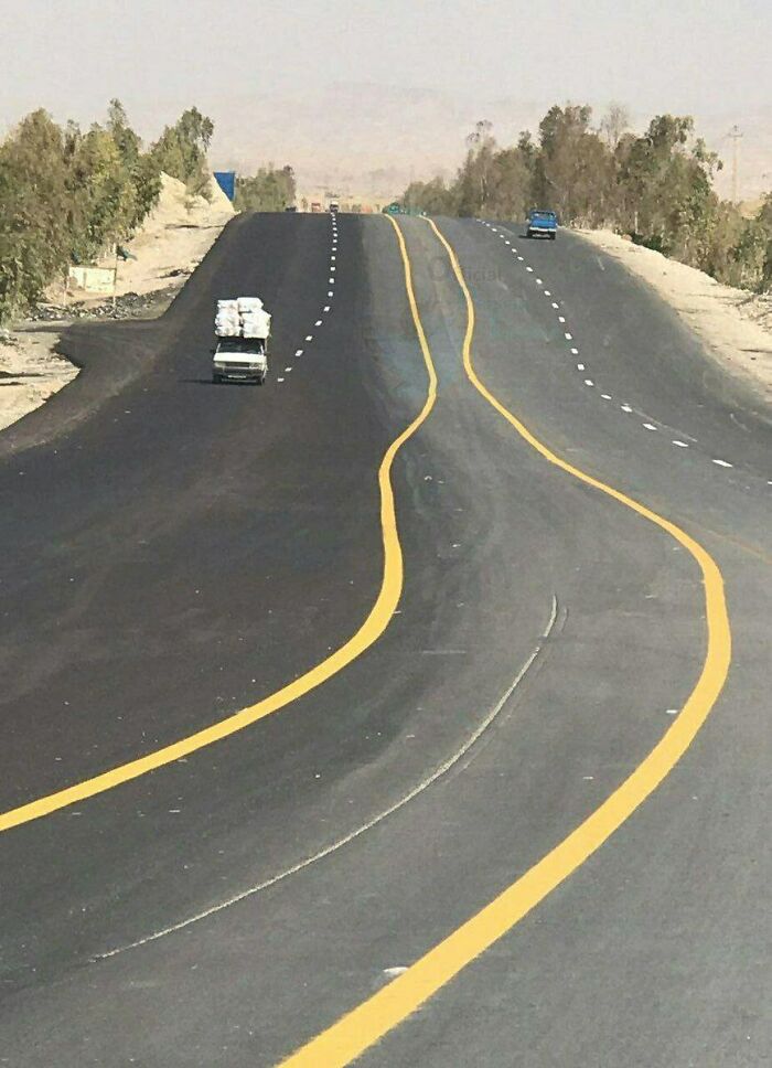 Poorly painted road lines curving awkwardly on a highway, illustrating funny examples of people not even trying.