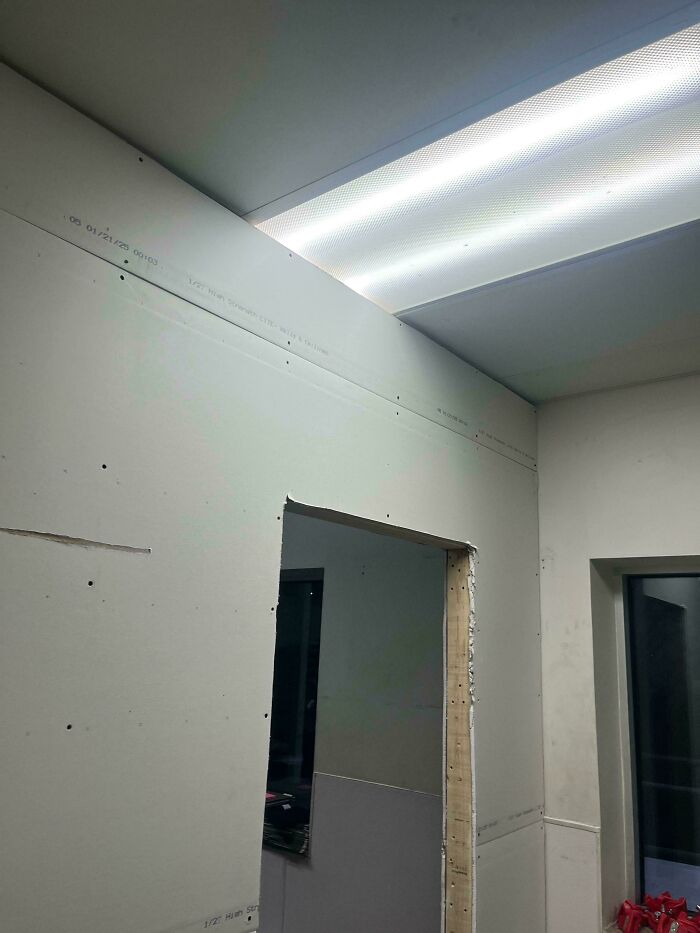 Unfinished drywall installation with rough door cutout showing a clear example of people not even trying in construction work.