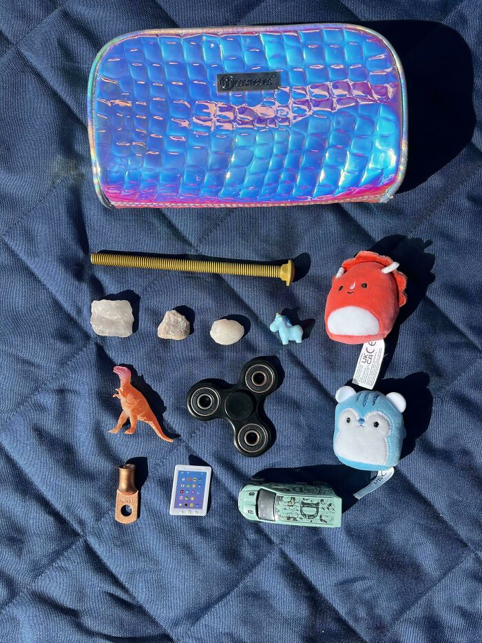 Neatly arranged small toys, rocks, and objects on blue fabric, showcasing satisfying all things knolled order.