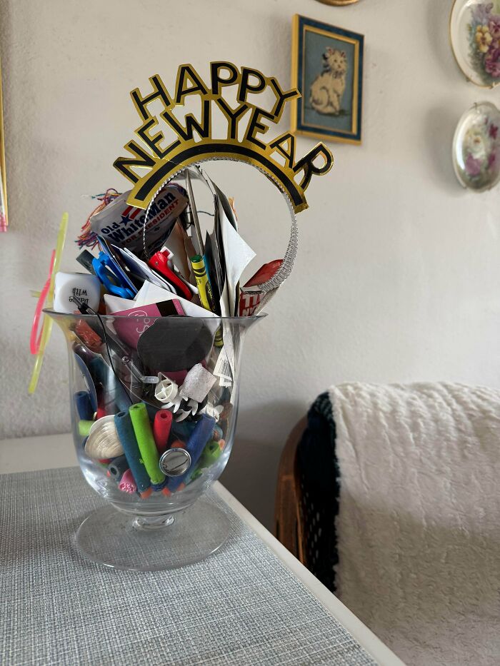 Clear glass container neatly filled with colorful items and a Happy New Year decoration, satisfying need for order.