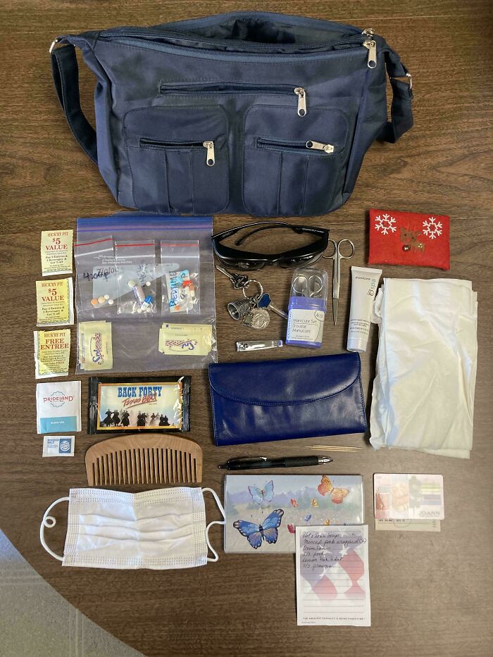 Knolled arrangement of personal items including bag, sunglasses, medication, toiletries, and notes on a wooden surface.