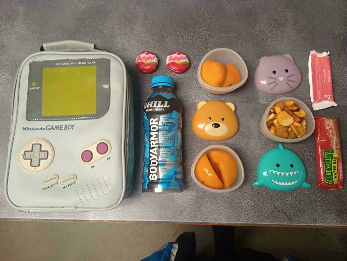 Neatly arranged food items, drink, and vintage Game Boy bag showcasing all things knolled for visual order.