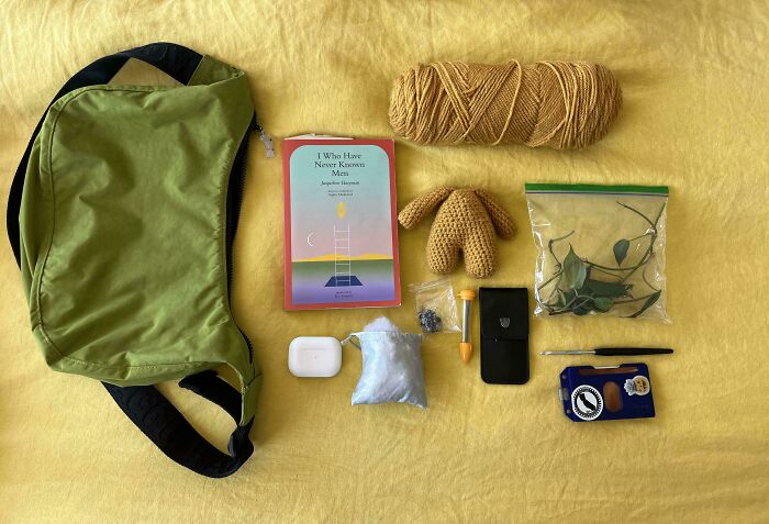 Neatly arranged everyday items including a green bag, book, yarn, and small objects illustrating knolled order and organization.
