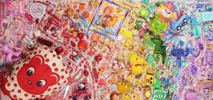 Colorful knolled arrangement of toys and small objects organized by hue from red to blue, showcasing satisfying order.