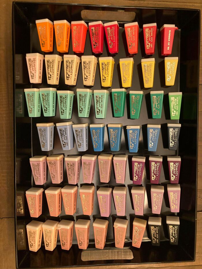 Colorful erasers neatly arranged by color in a black tray, showcasing satisfying order and organization.