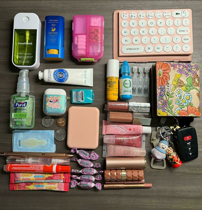 Neatly arranged personal items including cosmetics, keys, sanitizer, and a keyboard demonstrating satisfying need for order.