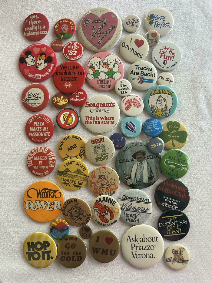 Collection of colorful vintage pins and badges neatly arranged on a white surface showing order and knolled organization.