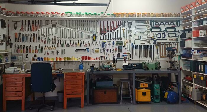Organized workshop with rows of hand tools on a wall, neatly arranged for order and satisfaction in tool storage.