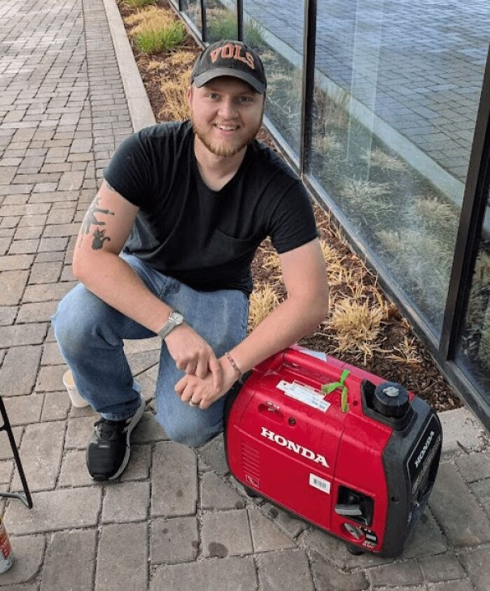 Young man smiling next to a red Honda generator, showing faith in humanity restored through acts of kindness.