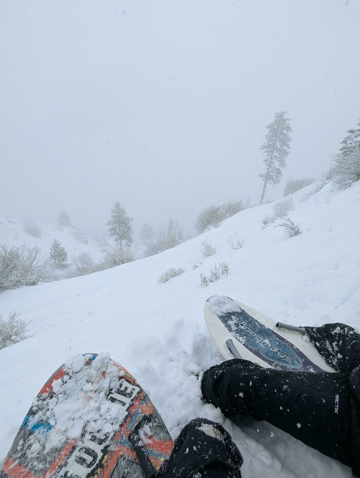 Snowboarders resting on a snowy slope in heavy snowfall, capturing frozen frames of a winter landscape adventure.