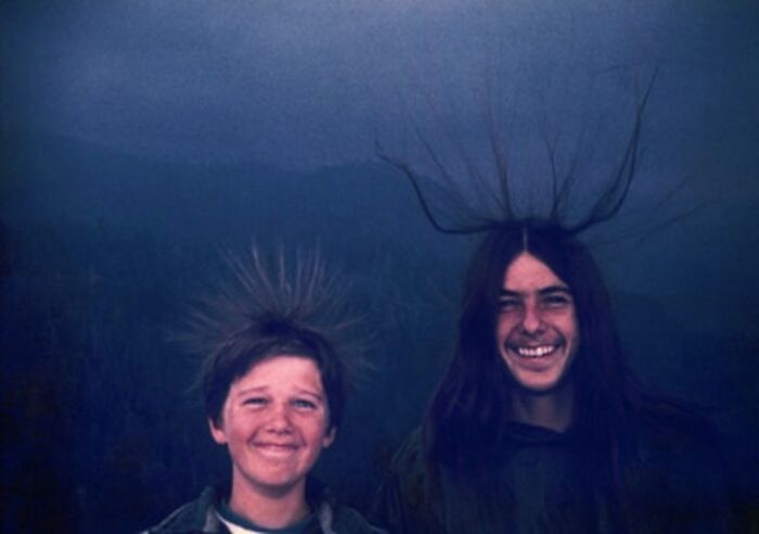 Two boys smiling with hair standing on end, captured in a frozen frame illustrating the electric charge effect.