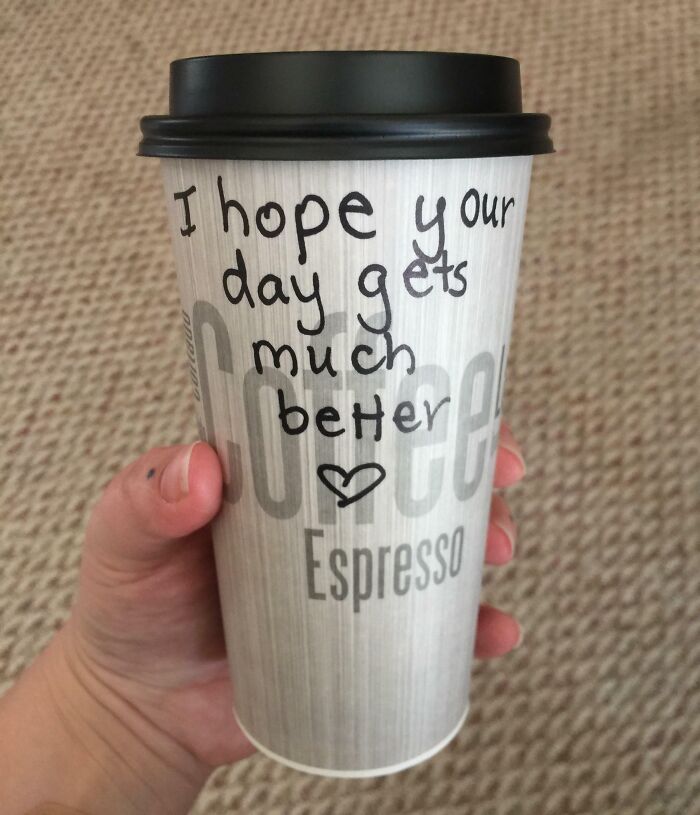 Hand holding espresso cup with handwritten message spreading kindness and faith in humanity restored.