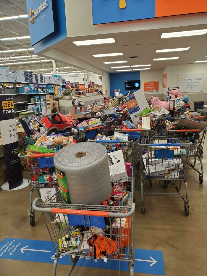 Multiple shopping carts overloaded with various items inside a busy store illustrating chaos on Black Friday.