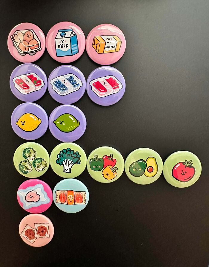 Colorful pins featuring cute food illustrations arranged on a black surface, showcasing creative projects by imaginative people.