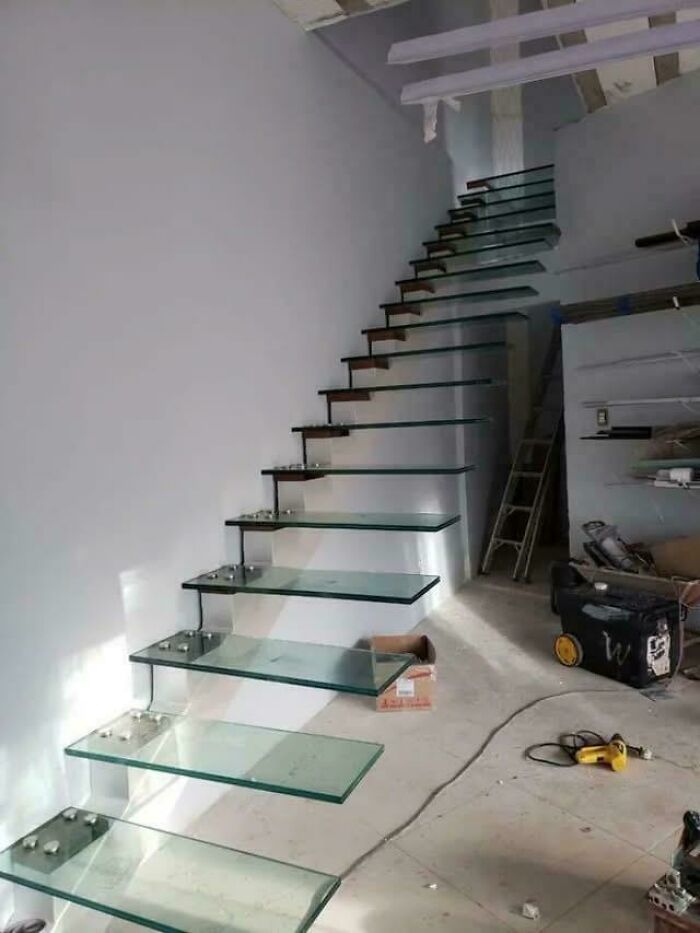 Glass stairs with no visible support in a construction site, illustrating Airbnb insanity and the need for insurance.