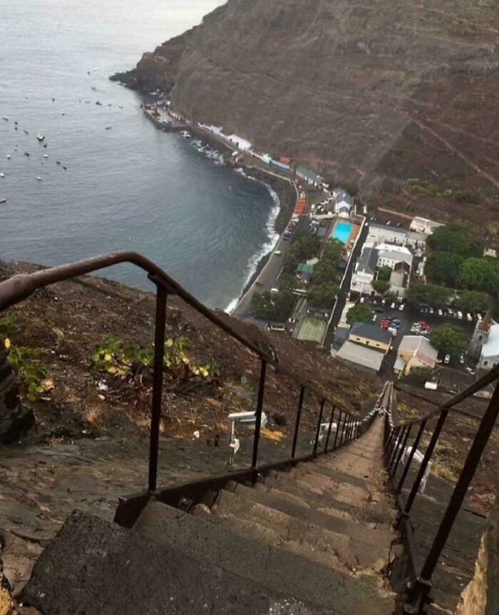 Steep stairs with railings overlooking coastal village and ocean, illustrating Airbnb insanity and high-risk stairs without insurance.