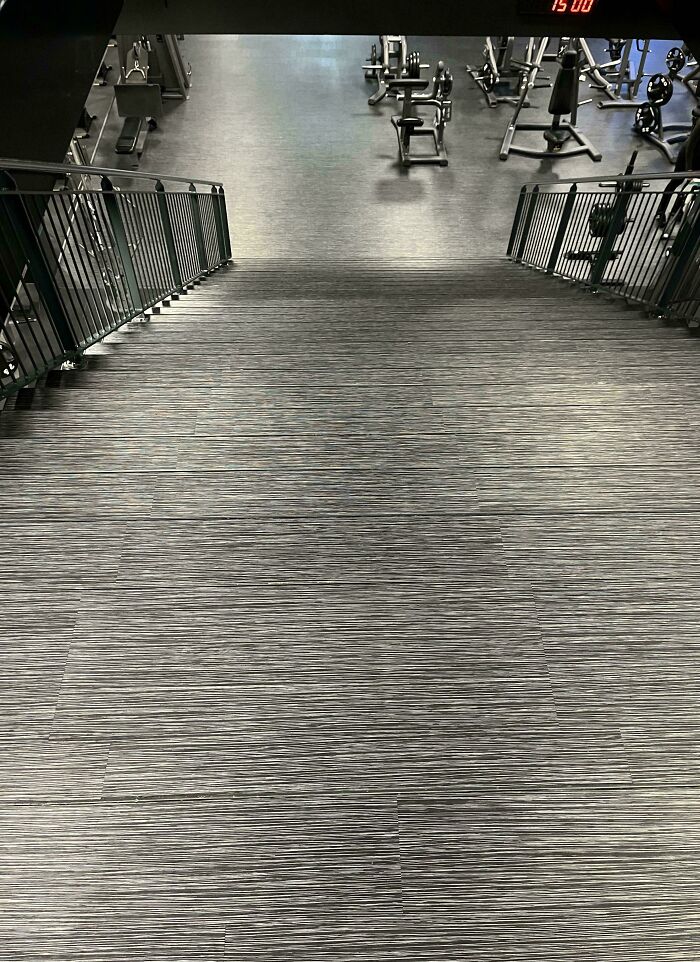 Long gray stairs with metal railings leading down into a gym area, illustrating Airbnb insanity stairs concept.