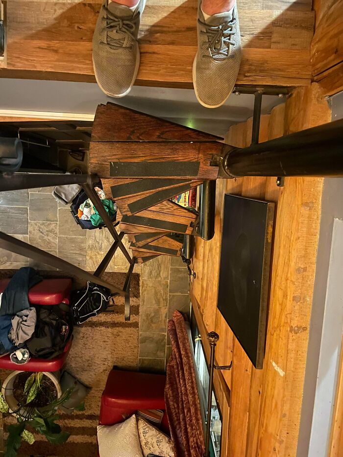 View looking down a narrow, steep wooden staircase in an Airbnb rental, emphasizing the need for Airbnb insurance safety.