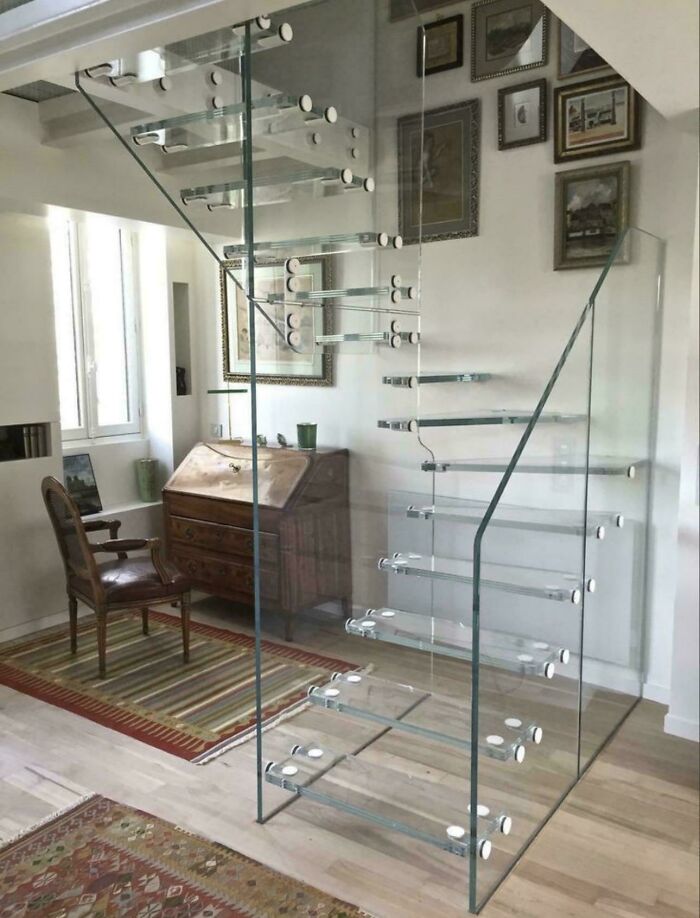 Modern glass stairs with floating steps inside a living room, illustrating Airbnb insanity with stairs needing insurance precautions.