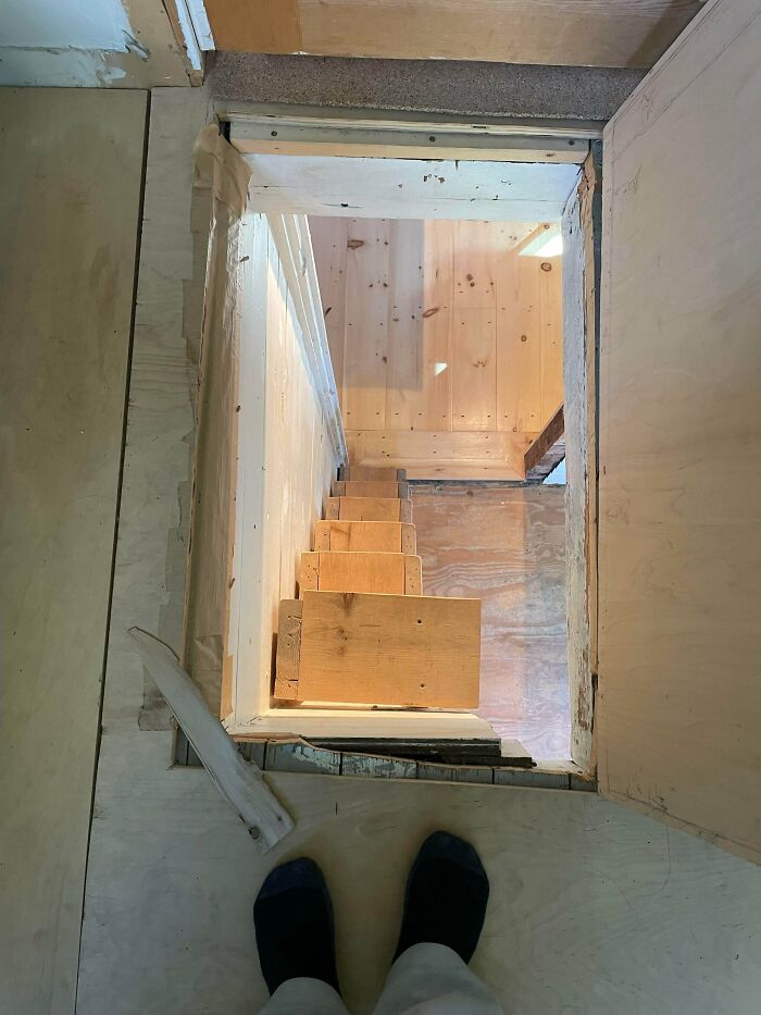 Steep narrow wooden stairs viewed from above in an unfinished space, illustrating Airbnb risks and insurance needs.