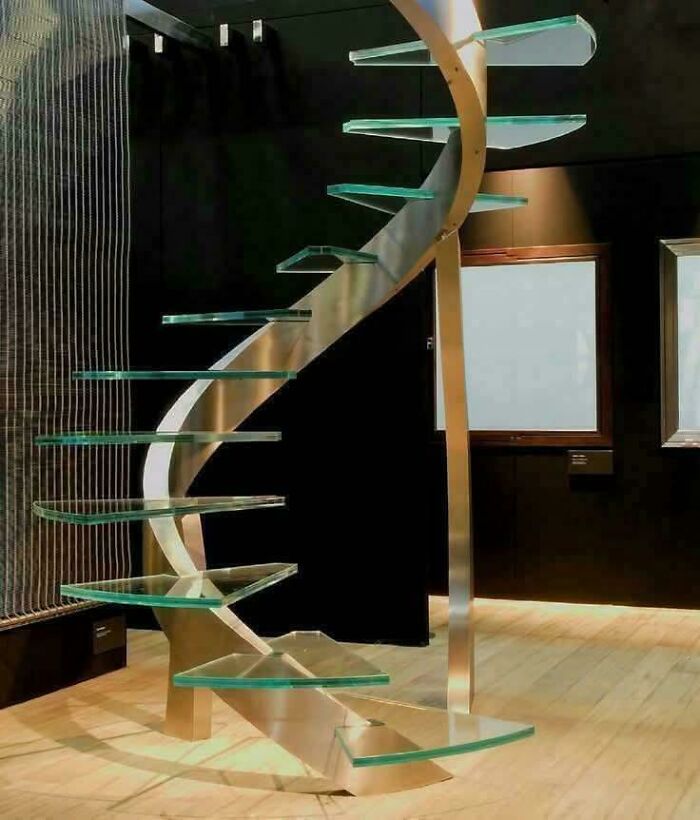 Spiral glass stairs with metal frame inside a room, highlighting Airbnb insanity risk and the need for insurance.
