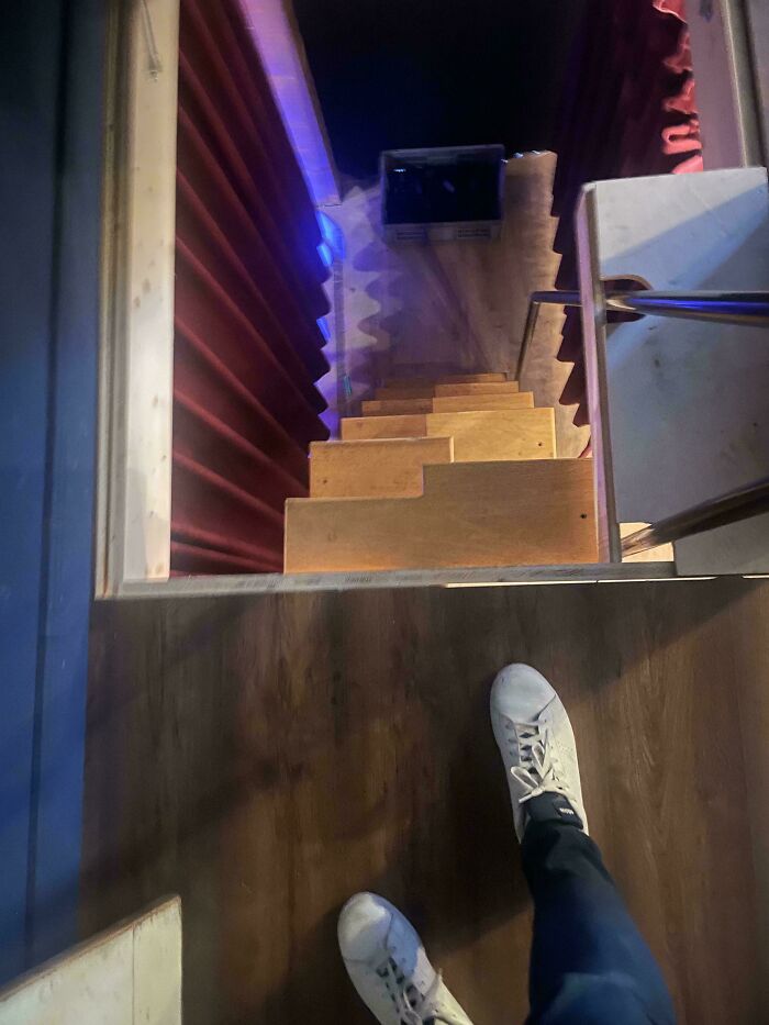 Steep narrow stairs viewed from above with white sneakers at the edge, highlighting Airbnb stairs insurance risks.