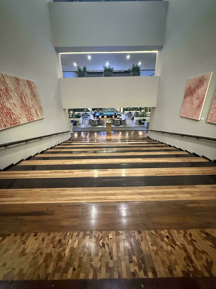 Wide wooden staircase inside a modern Airbnb property with sleek design and decorative abstract wall art on both sides.