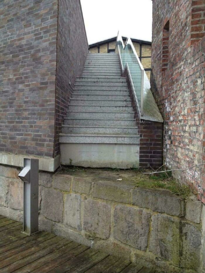 Narrow concrete stairs with glass railing leading up between two brick walls, illustrating Airbnb insanity risk.