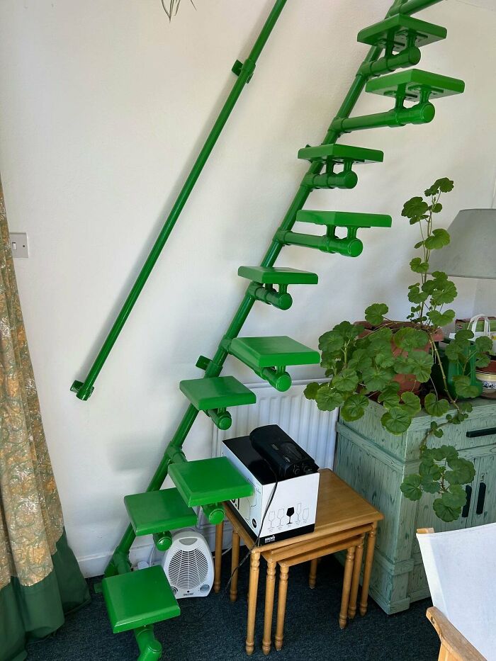 Steep green stairs with small platforms inside a room, illustrating the need for Airbnb insurance for risky stairs.