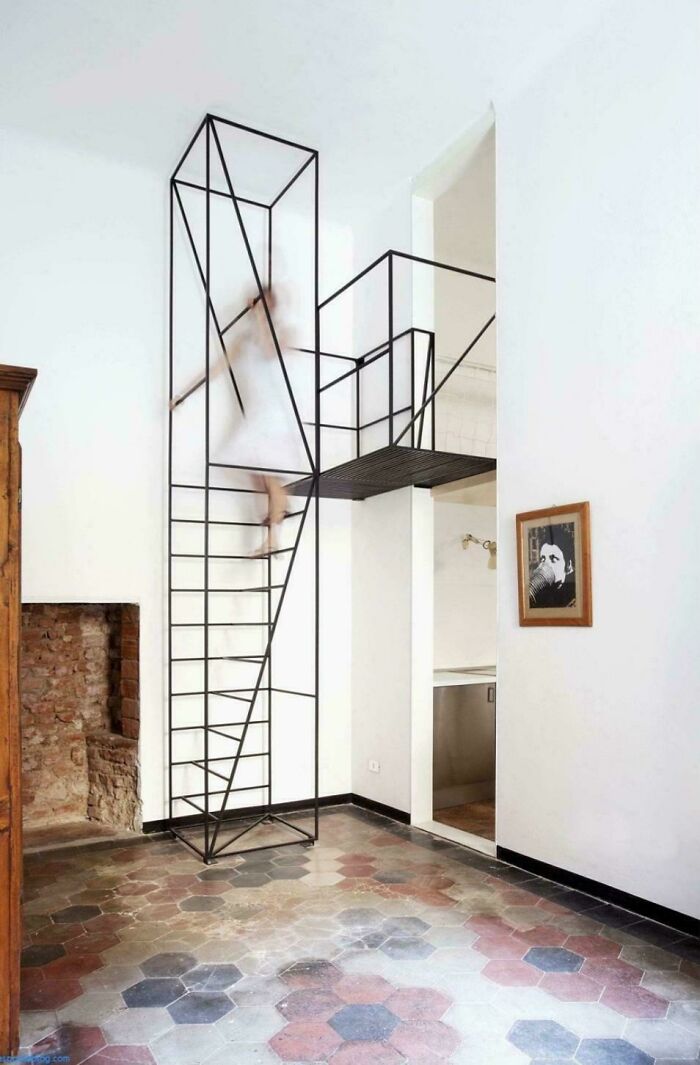 Minimalist metal stairs inside a bright Airbnb space with a blurred figure ascending, highlighting Airbnb insurance safety concerns.