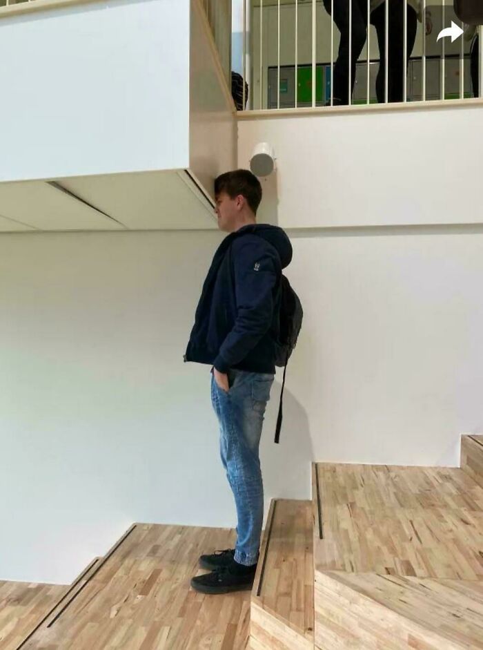 Young man standing on awkward wooden stairs indoors, illustrating Airbnb insanity and the need for insurance with tricky staircases.