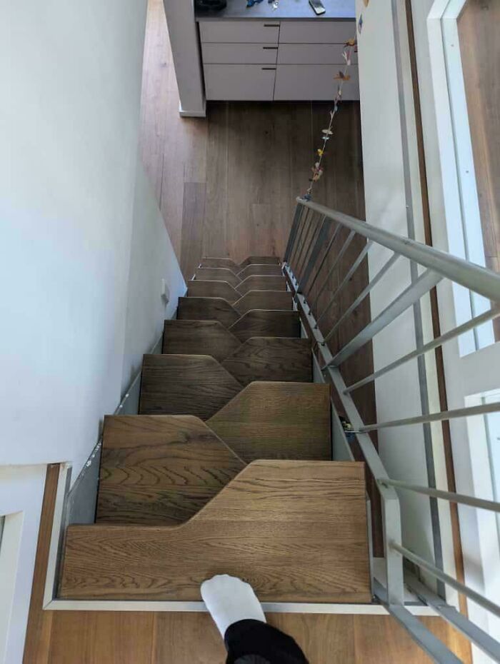 Steep wooden stairs with odd cuts and a metal railing in an Airbnb setting highlighting the need for insurance precautions.