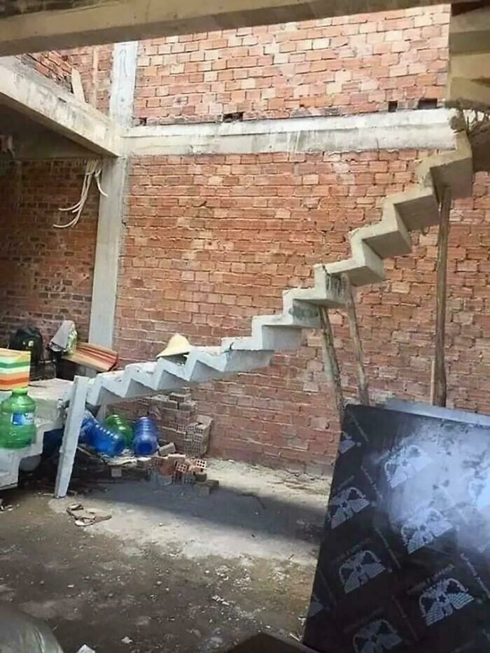 Unfinished floating concrete stairs in a brick building under construction showing potential Airbnb insurance risks.