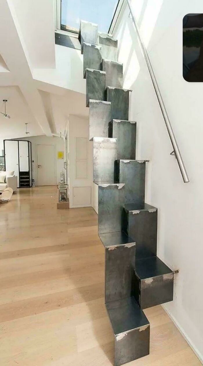 Metal staircase with irregular steps in a modern Airbnb interior, highlighting the need for insurance due to safety risks.