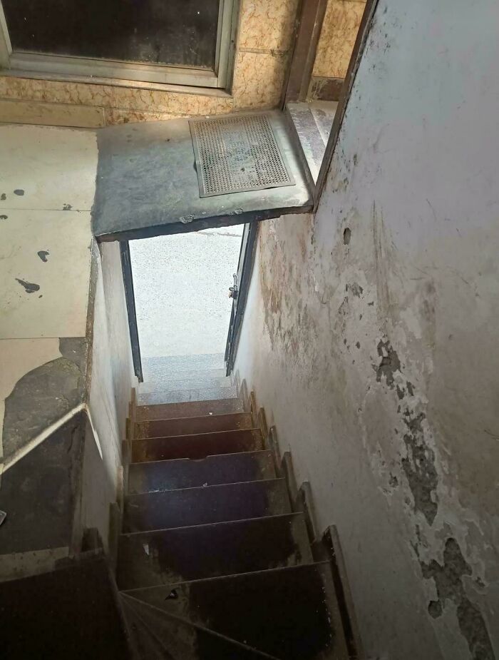 Steep narrow stairs with worn walls and a precarious landing, illustrating Airbnb risks that require insurance coverage.