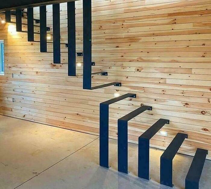 Floating black metal stairs attached to a wooden wall in a modern interior, highlighting Airbnb insurance risks.