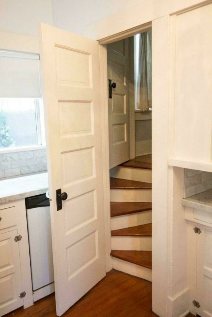 Narrow wooden spiral stairs in a small kitchen doorway, illustrating Airbnb insanity and the need for insurance precautions.