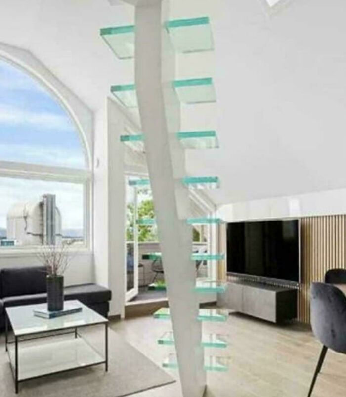 Modern living room with a unique glass floating staircase representing Airbnb stairs requiring insurance caution.