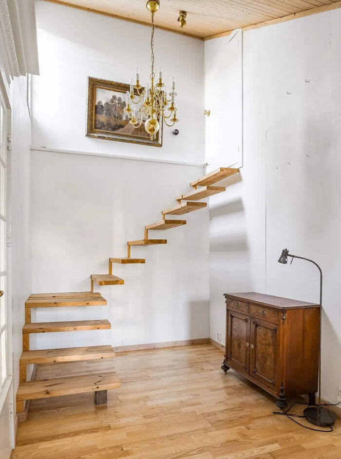 Floating wooden stairs with no railing in a minimalistic Airbnb interior, highlighting Airbnb insurance safety concerns.