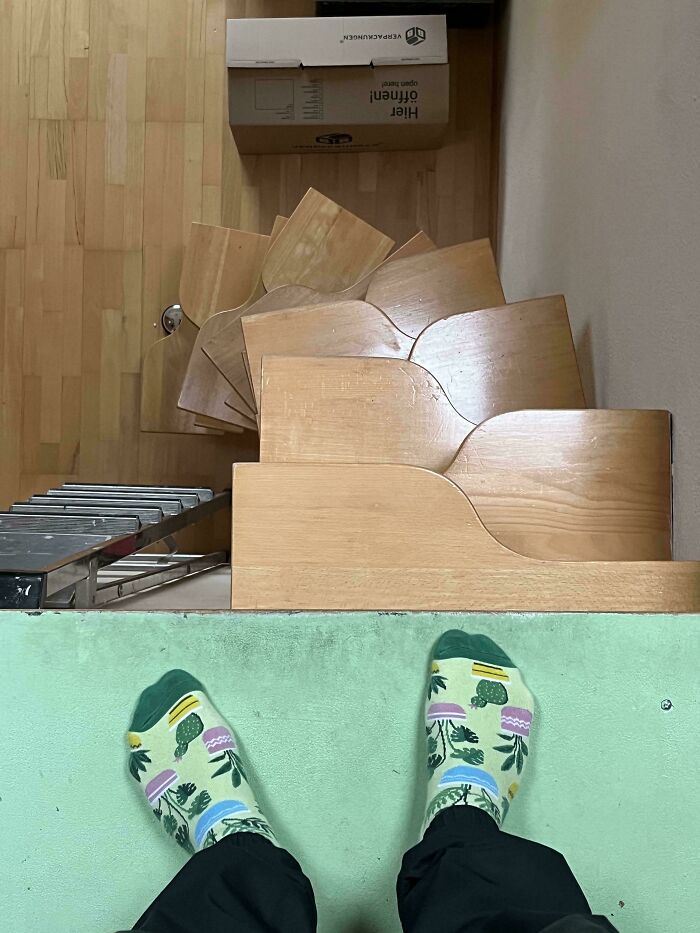 View looking down a steep wooden spiral staircase with colorful socks visible and a box at the bottom, illustrating Airbnb stairs risk.