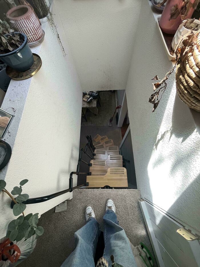 View looking down a narrow staircase in an Airbnb rental with 130 stairs and a handrail on the left side.
