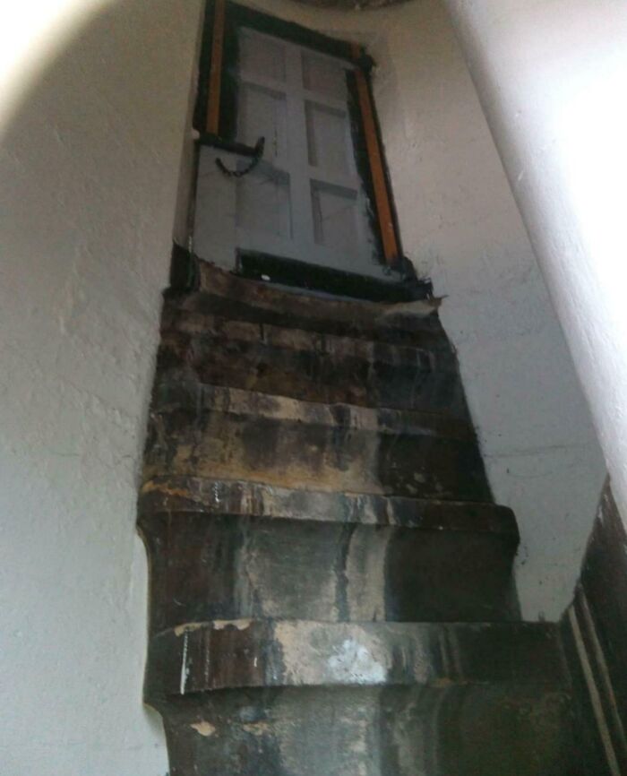 Steep narrow stairs leading up to a closed door in a confined space, illustrating Airbnb insanity and insurance risks.