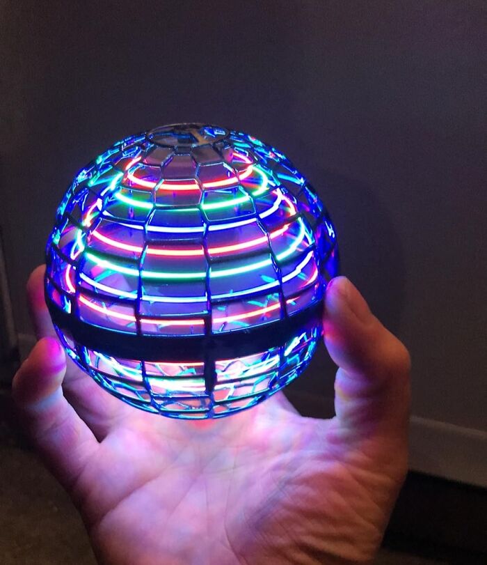 Hand holding a glowing spherical LED gadget with colorful lights, a fun and unnecessary novelty find.