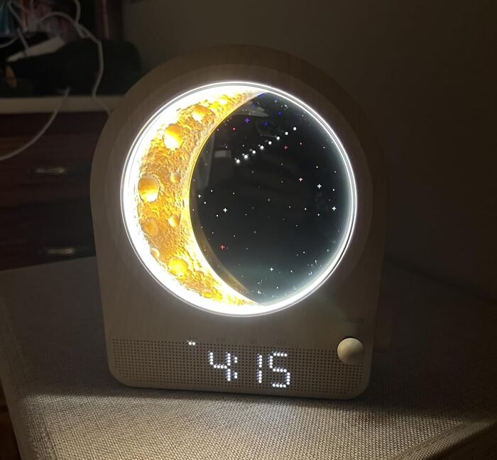 Novelty clock with moon and stars design softly illuminated, showcasing unique and unnecessary novelty finds for decor.