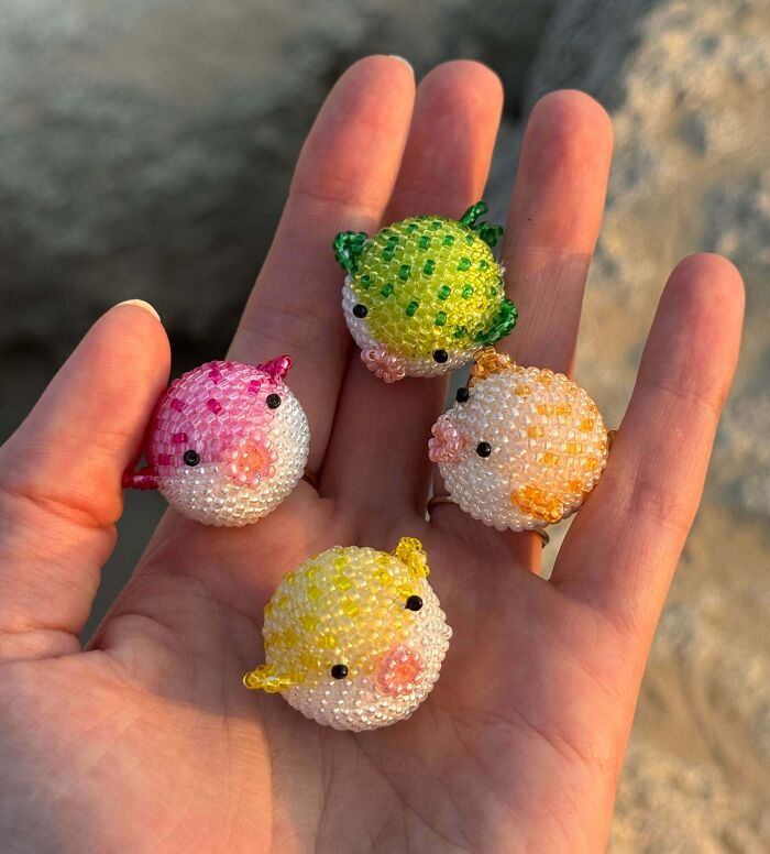 Hand holding four creative beaded animal projects, showcasing detailed and colorful handmade art pieces.