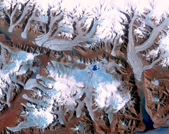 Aerial view of remote icy mountain glaciers and rugged terrain in an isolated location with snow and ice formations.