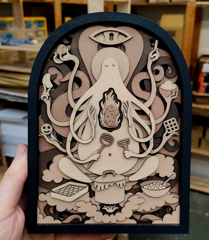 Handcrafted layered wood art of a multi-armed figure cooking, showcasing creative people and cool projects with intricate detailing.