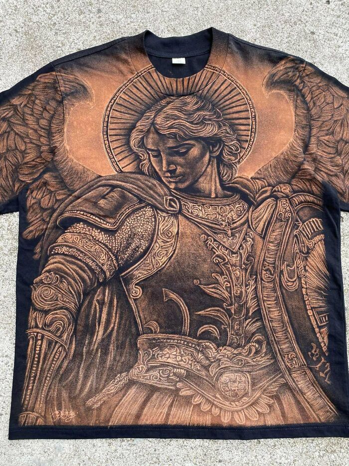 T-shirt featuring detailed artwork of an angelic figure with armor and wings, showcasing creative projects by artists.